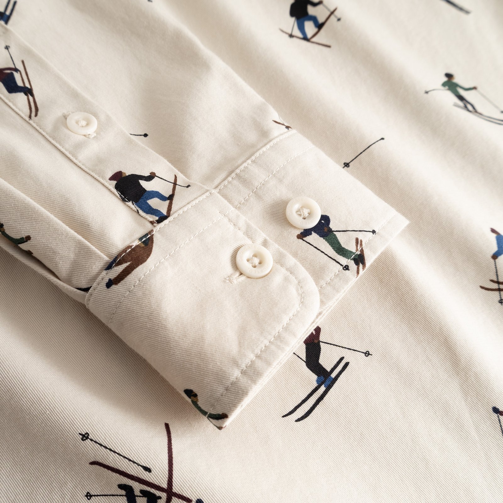 A close-up detail of the cuff on the oat white Shirt Lunnevik, showcasing the fun all-over ski team print.
