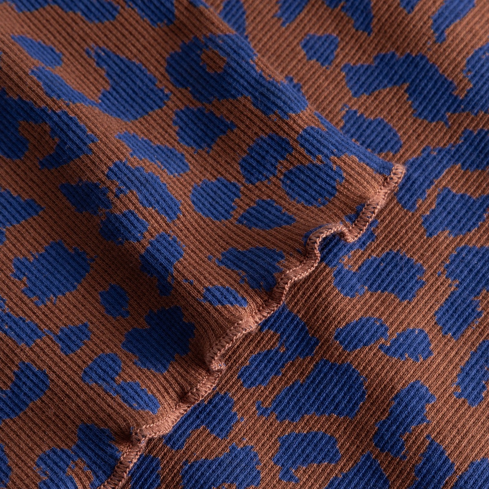 A close-up of the Rib Dress Lofta in a playful blue and brown leopard print, showing soft ribbed texture and lettuce seam.