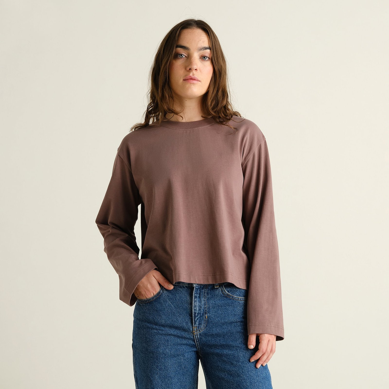 Model wearing the long-sleeved Vreta T-shirt in Sparrow Brown, showing its relaxed, boxy fit with wide sleeves.