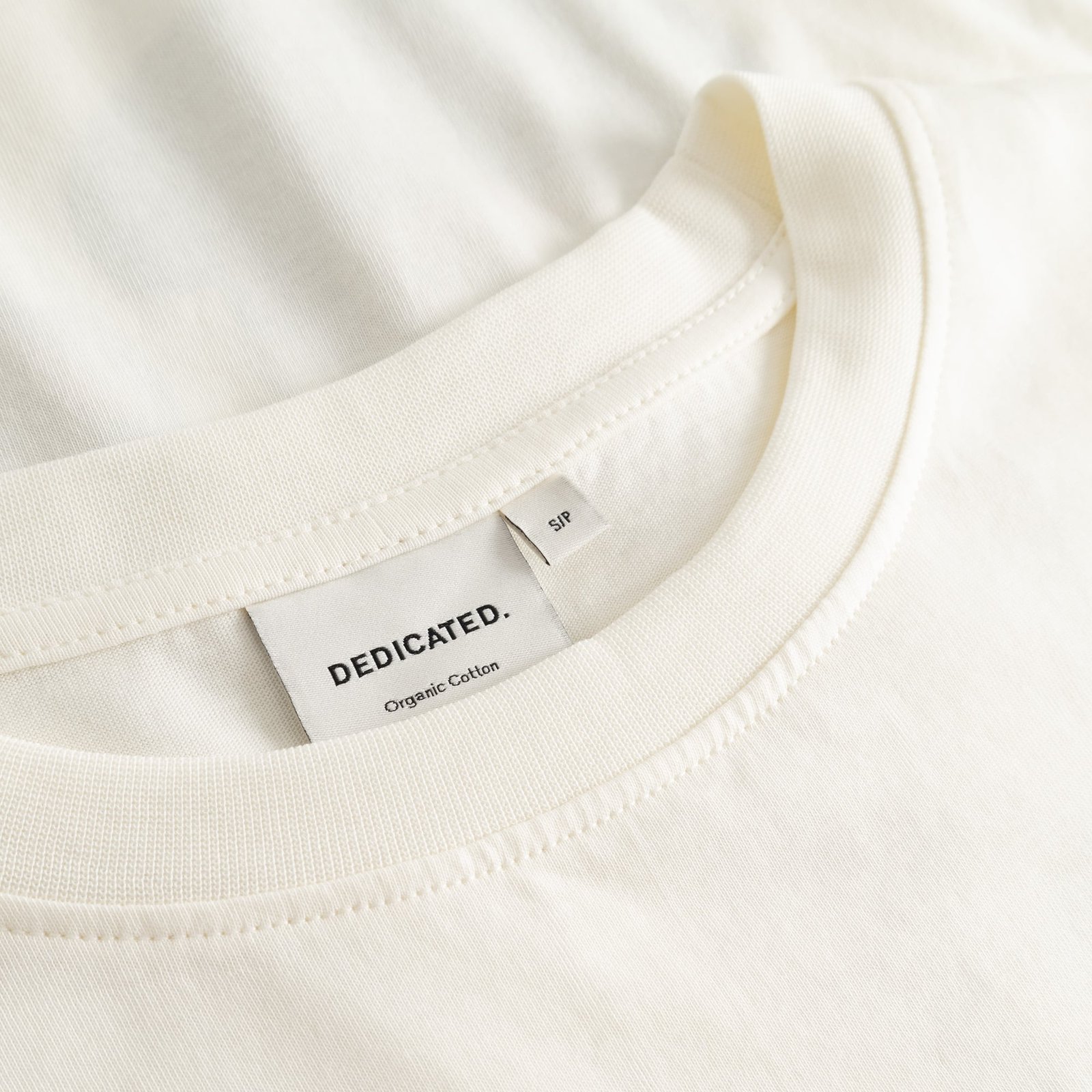Close-up detail shot of the ribbed crew neck collar and brand label inside the off-white T-shirt Vadstena Autumn Harvest.