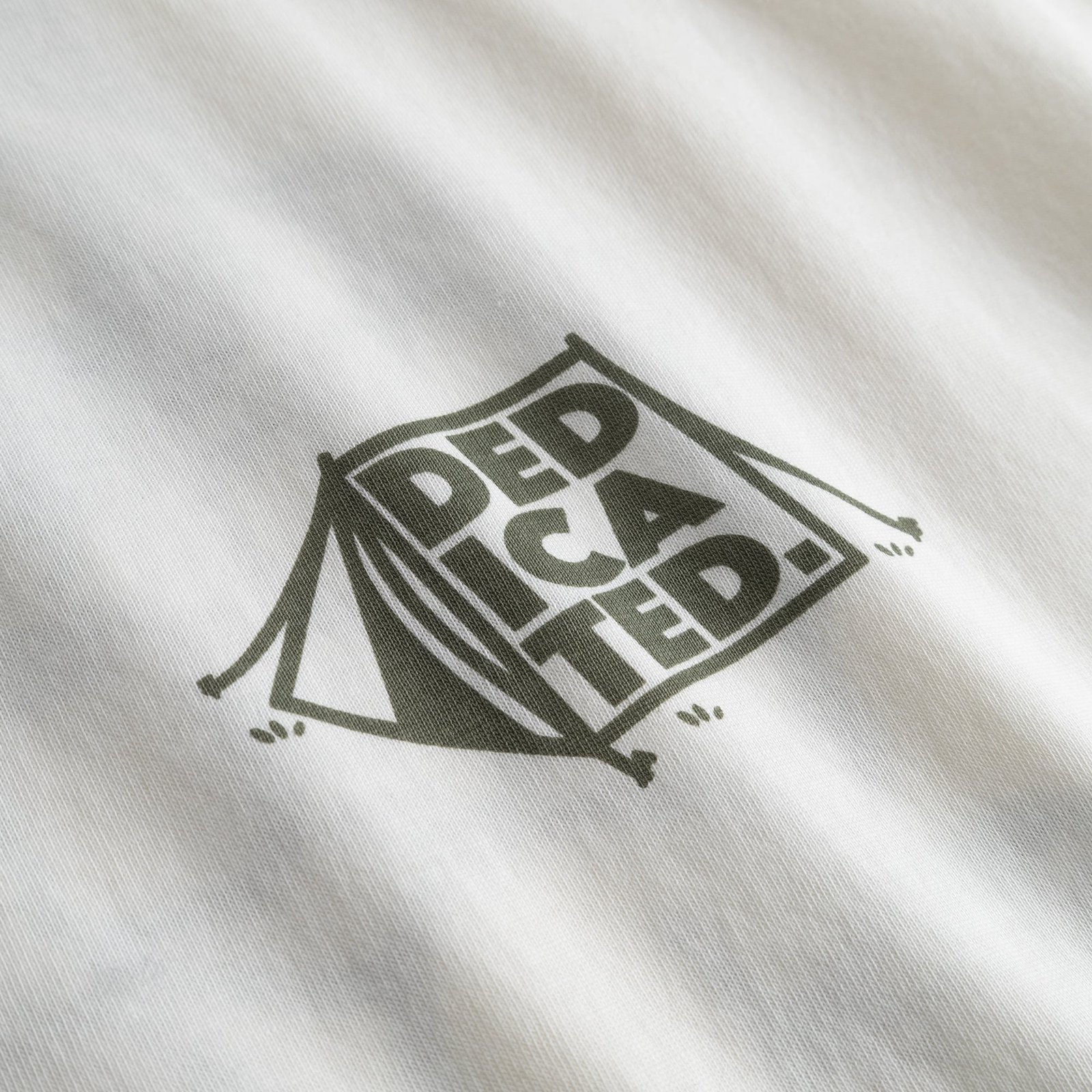 Close-up shot of the off-white T-shirt Stockholm, detailing the green 'Dedicated' tent graphic on the organic cotton fabric.
