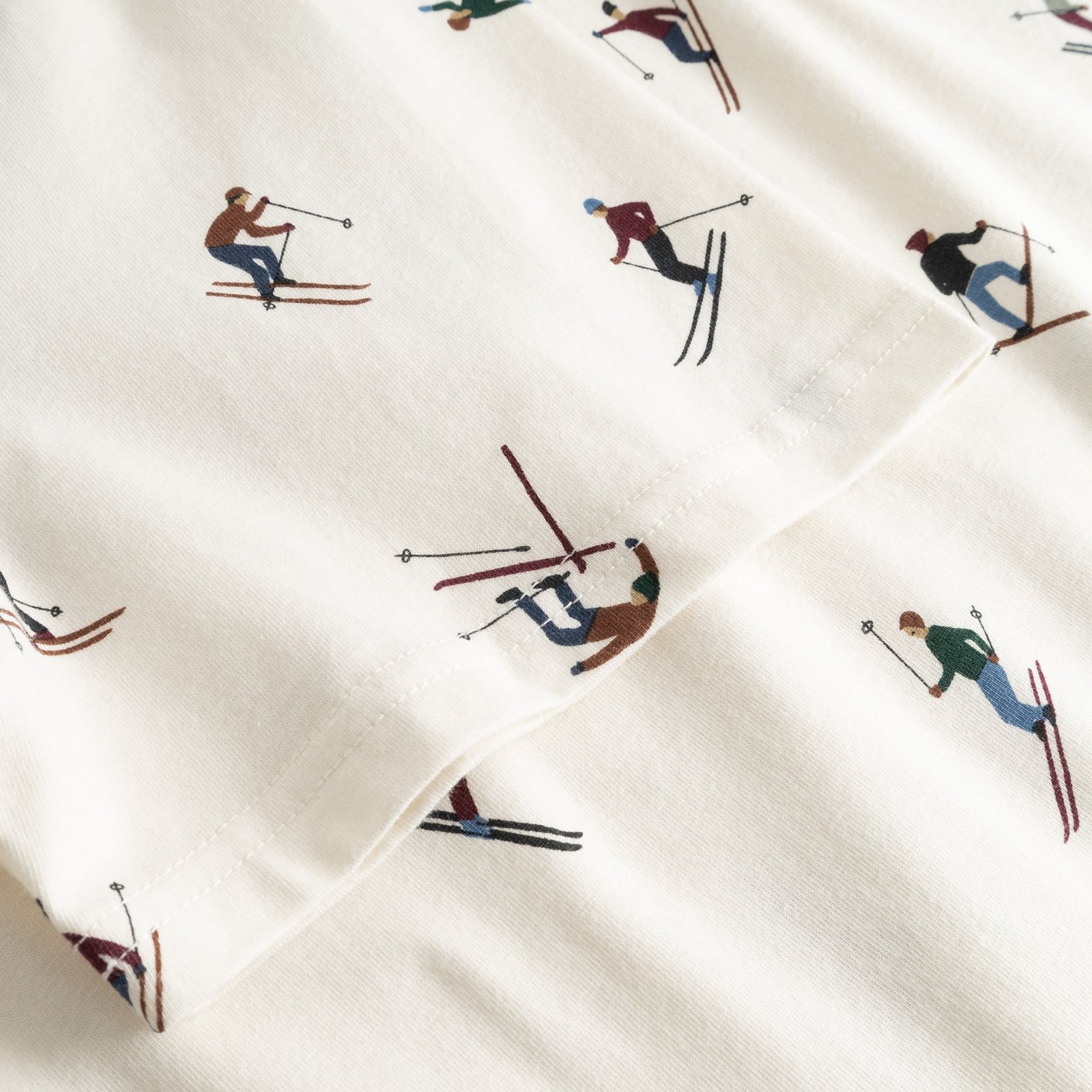 Close-up detail of the off-white Stockholm Ski Team t-shirt, showing the all-over print of colorful skiers on the sleeve.