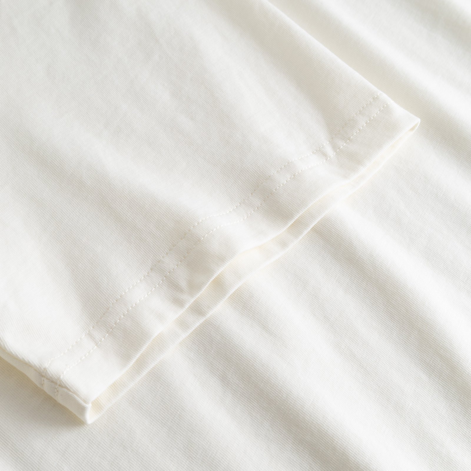 A close-up shot of the sleeve on the off-white T-shirt Stockholm Perch EMB, highlighting the soft organic cotton fabric.