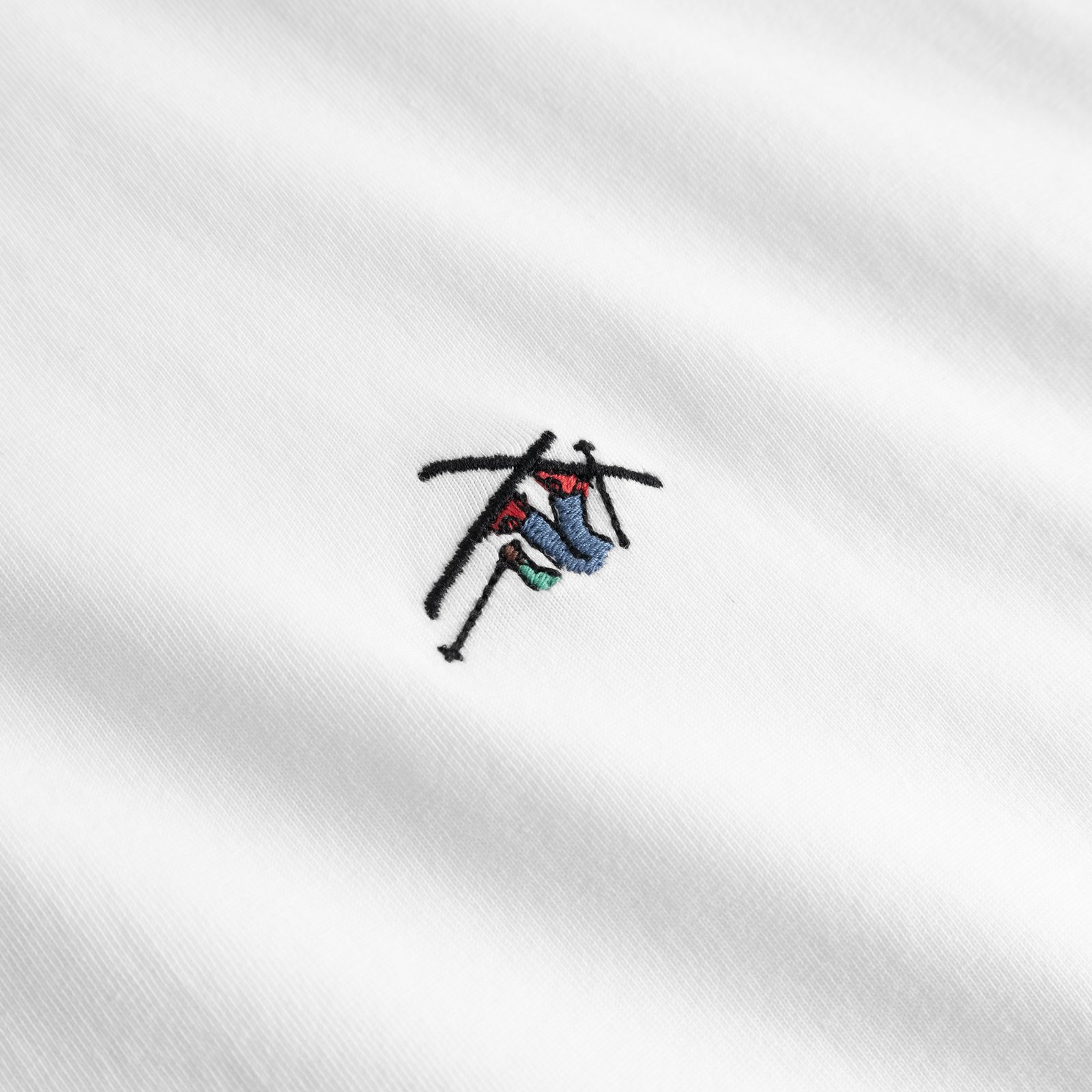 Close-up of the playful Ski Crash embroidery on the white T-shirt Stockholm.