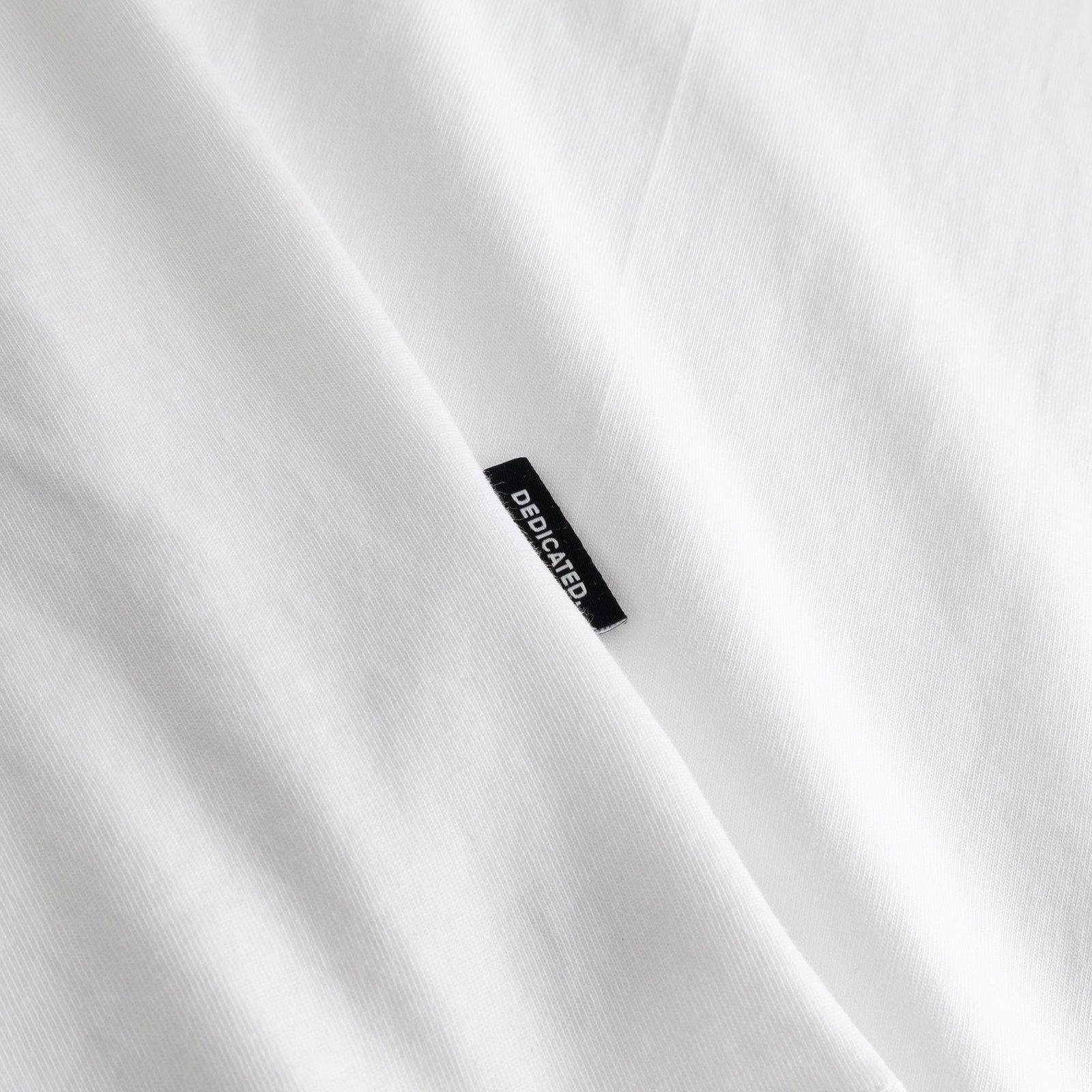 Detail shot of the white T-shirt Stockholm showing the soft fabric and our classic black and white Dedicated brand tab.
