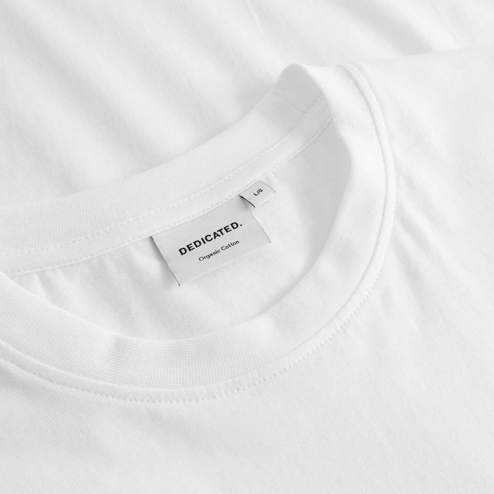 Close-up of the ribbed crew neck and brand label on the white T-shirt Stockholm Friday Celebration.