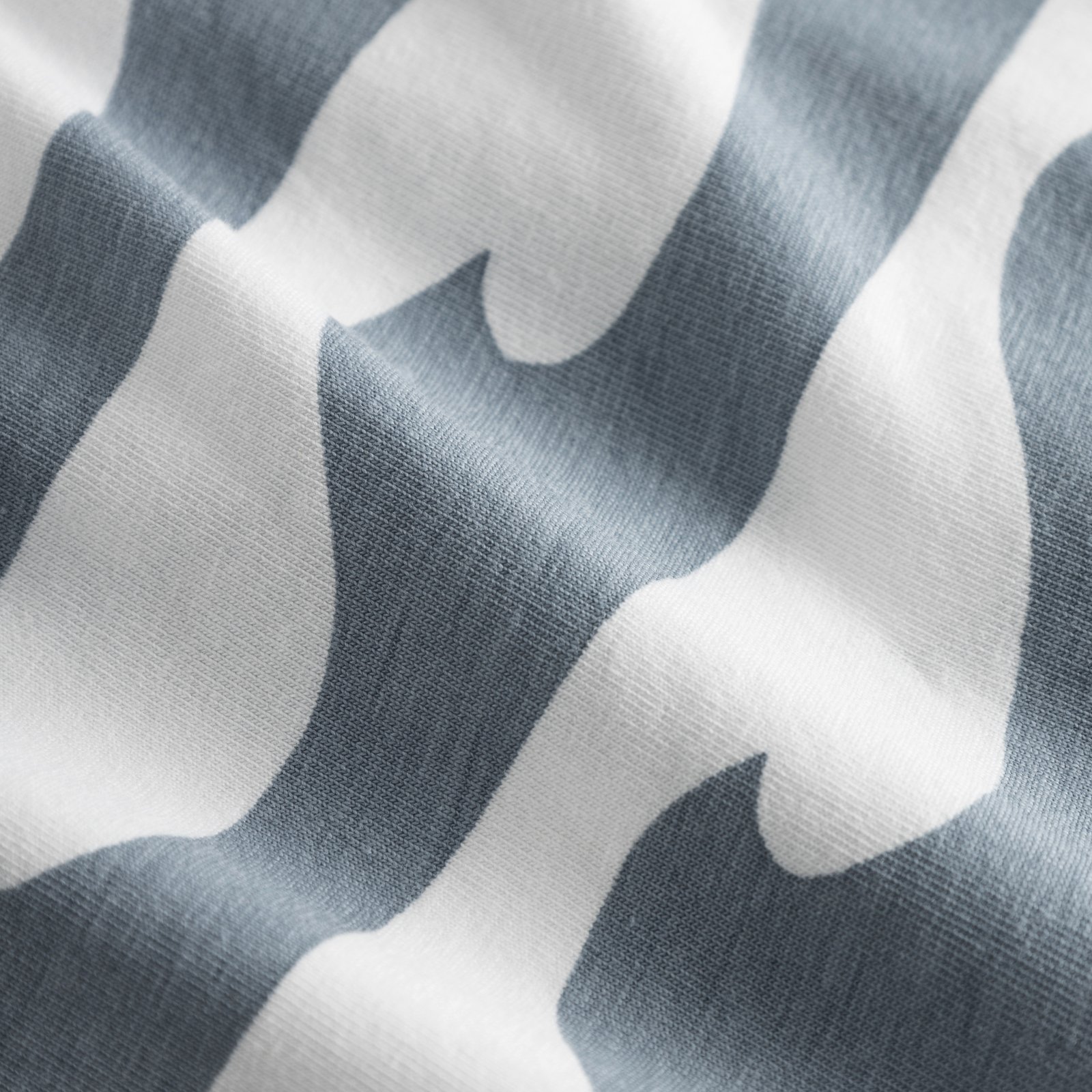 Nahaufnahme des weichen Bio-Baumwolljerseys der Kalix Boxershorts mit weiß-blauem Wellenmuster.